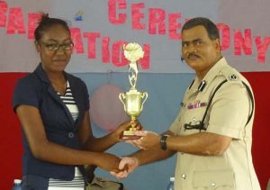 Acting Commissioner of Police David Ramnarine presents a graduate with her trophy.