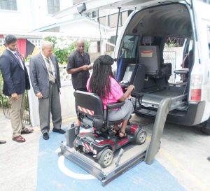 Minister George Norton (second from left) is given a demonstration of the functions of the wheelchair bus.