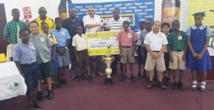 Petra’s Troy Mendonca (centre) receives the sponsorship cheque from Courts Managing Director Clyde de Haas in the presence of GFF President Wayne Forde (3rdfrom left), Malta Brand Manager Clayton McKenzie (2nd from left) and students yesterday.