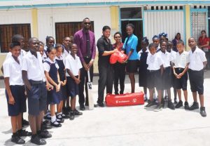 Director of Sports Chris Jones watch as Sarwan presents an autographed bat and Scotiabank Kiddies gear to the Stella Marris cricket team. 