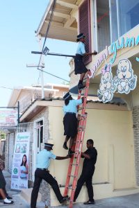 Police ranks utilising a ladder to gain entry into the North Shore Medical School, on Lamaha Street, Georgetown. 