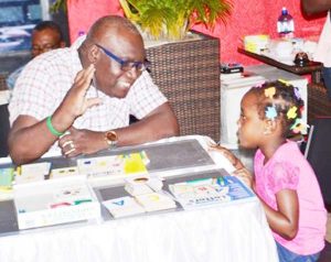 Marcel Hutson, Chief Education Officer (acting), Ministry of Education interacting with one of the participants at the literacy clinic held at Princess / Ramada Fun City.