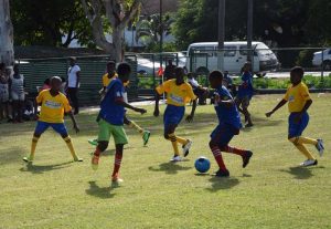 Players from J.E. Burnham and West Ruimveldt battle for possession in their clash which the latter won at Thirst Park yesterday.