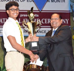 Prime Minister Nagamootoo (Acting President) hands over a trophy to the Most Outstanding CSEC performer, Kayshav Tewari. (Photo Credit: Courdel Jones)