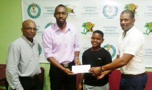 Director of Sport, Christopher Jones (second, left) hands over the contribution to the ‘Baby faced assassin’ Kaysan Ninvalle, while GTTA President, Godfrey Munroe (right) and Coach, Linden Johnson (left) also share the moment.