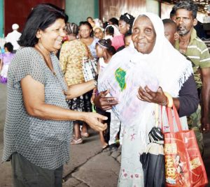 Mrs. Ameena Gafoor (left) is all smiles as she  hands over a blanket to one of the guests.