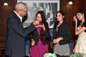  CAPTION: President David Granger gives Ms. Radha Mansaram a piece of her birthday cake as her sisters look on.