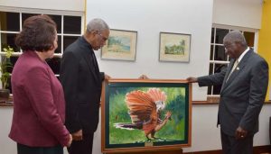 President David Granger, accompanied by First Lady, Mrs. Sandra Granger handing over the gift of a wooden sculpture called the ‘The Chief Witness to the Environment’ to Prime Minister Freundel Stuart.