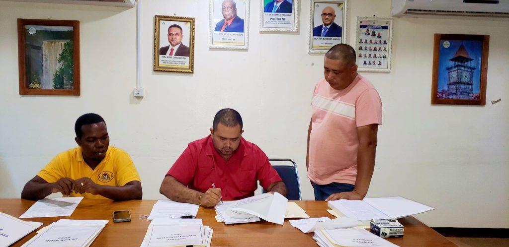 Regional Executive Officer (REO) of Region Nine, Karl Singh (center) signing the contracts along with the contractors on Monday.