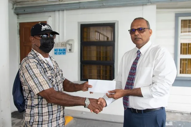Health Minister, Dr. Frank Anthony hands over the assistance to one of the patients